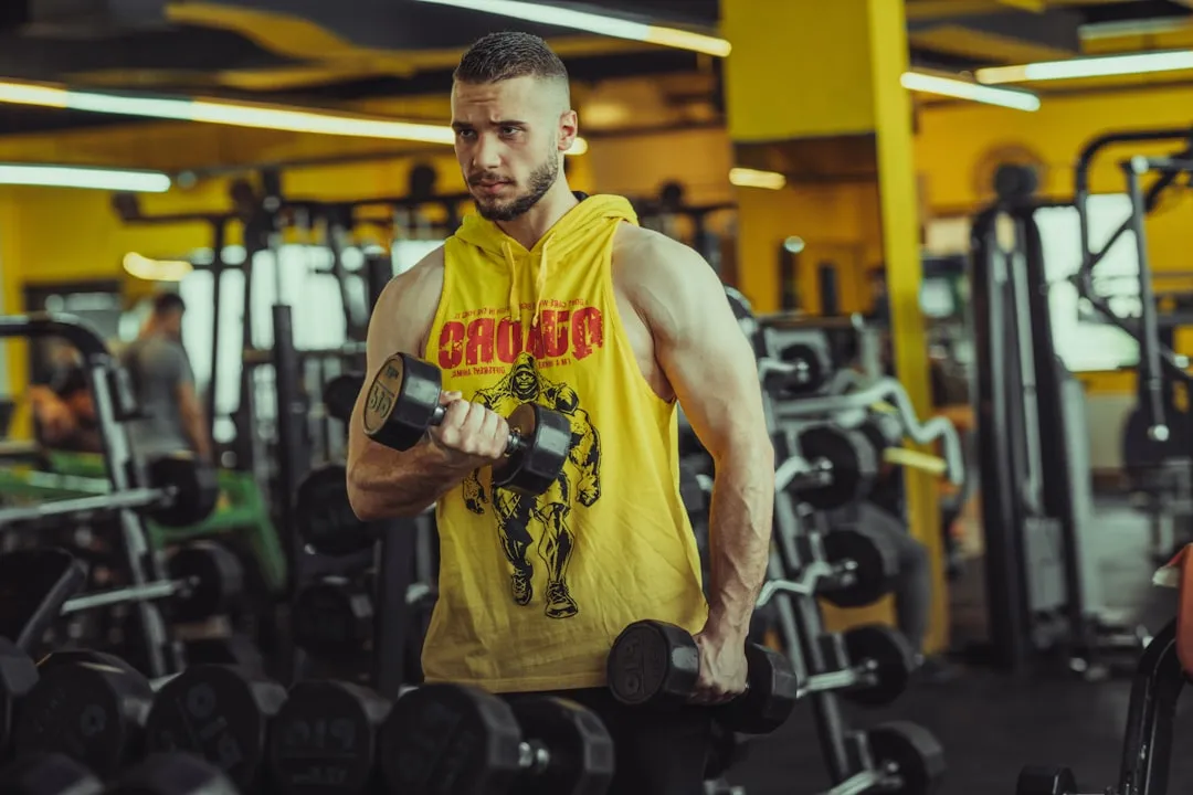 a man in a gym holding a pair of dumbs