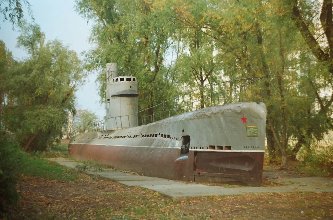 An old submarine sits on display among trees.