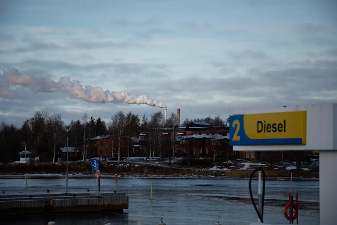 smoke billows from a factory near a body of water