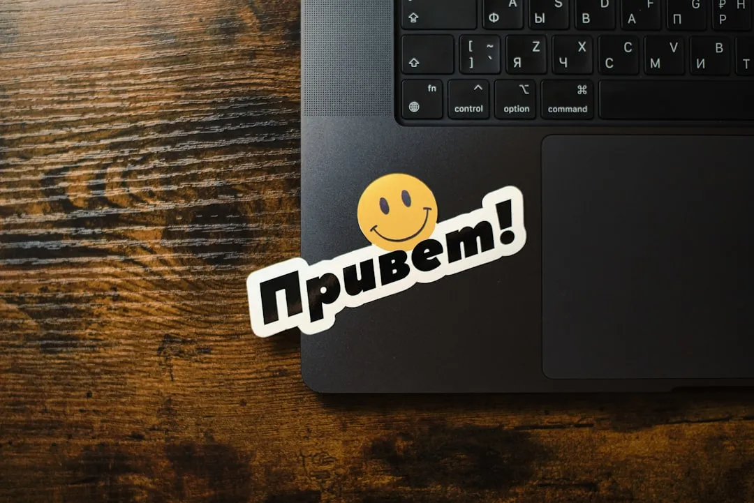 A smiley face sticker with привет! on a laptop.