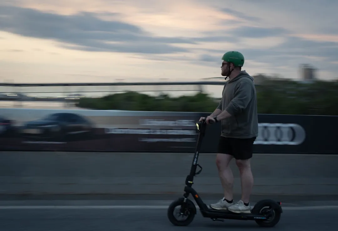 Man riding an electric scooter with a helmet.
